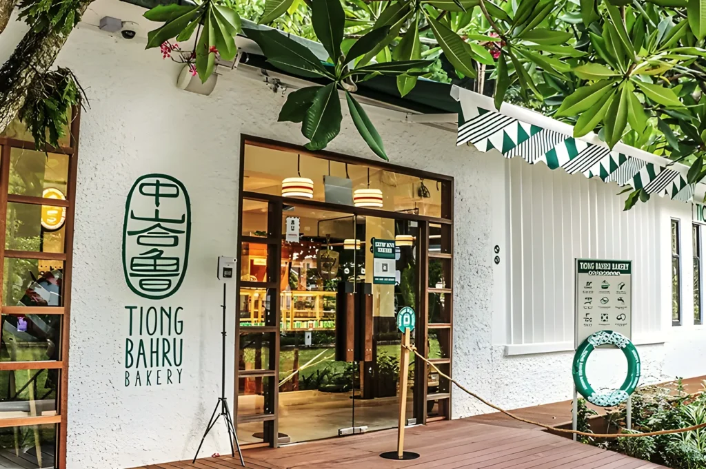 Tiong Bahru Bakery exterior with signature green logo, wooden doors, and leafy surroundings — iconic Singapore bakery offering artisanal pastries.