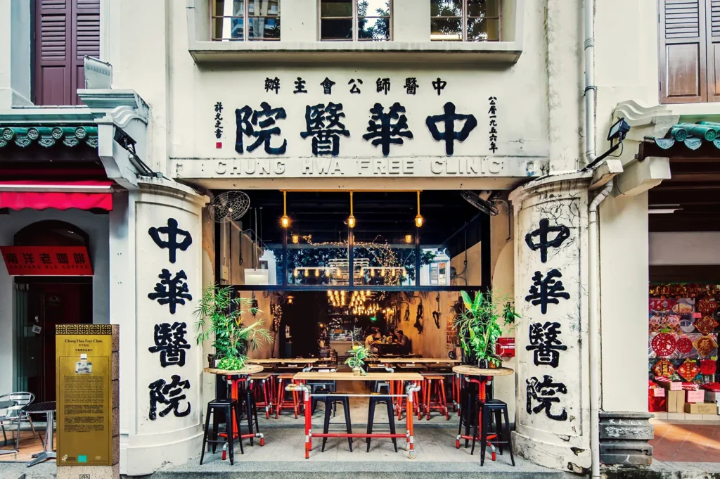 Chung Hwa Free Clinic heritage building in Singapore, now a trendy café with preserved Chinese calligraphy façade and warm interior lighting, showcasing cultural architecture and modern reuse.