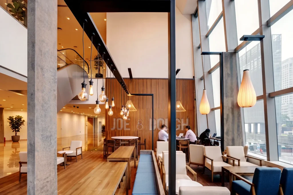 Spacious Joe & Dough café with floor‑to‑ceiling windows, wooden décor, and ambient lighting — elegant coffee lounge for work and relaxation.