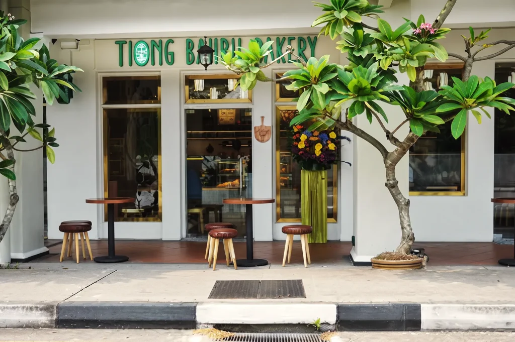 Tiong Bahru Bakery entrance surrounded by lush greenery and outdoor seating in Singapore