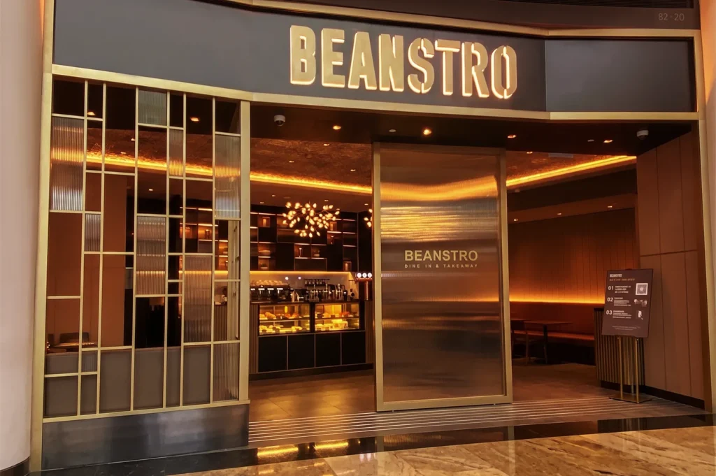 Beanstro Singapore café entrance with gold accents, warm lighting, and dine‑in and takeaway counter.