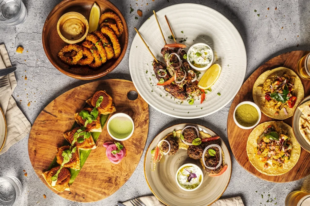 Flat lay spread of international tapas, grilled skewers, tacos, and dips at The Dempsey Project.