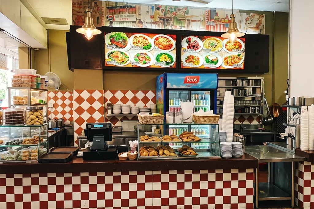 YY Kafei Dian pastry counter showcasing curry puffs, buns, and traditional snacks beside Yeo’s beverage fridge — vibrant local café interior in Singapore.