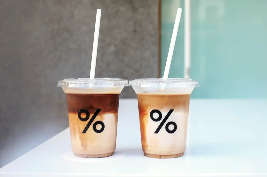 Two % Arabica iced lattes with layered espresso and milk in clear cups featuring signature percent logo.
